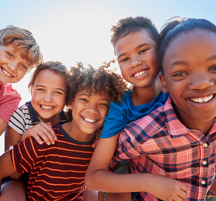 A group of kids on each others shoulders smiling.