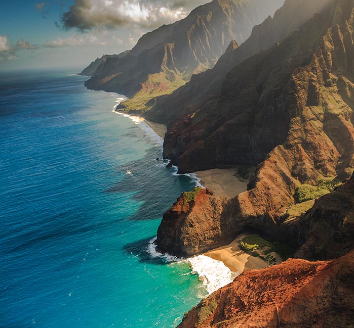 A view of mountains above beaches at a calm blue ocean.